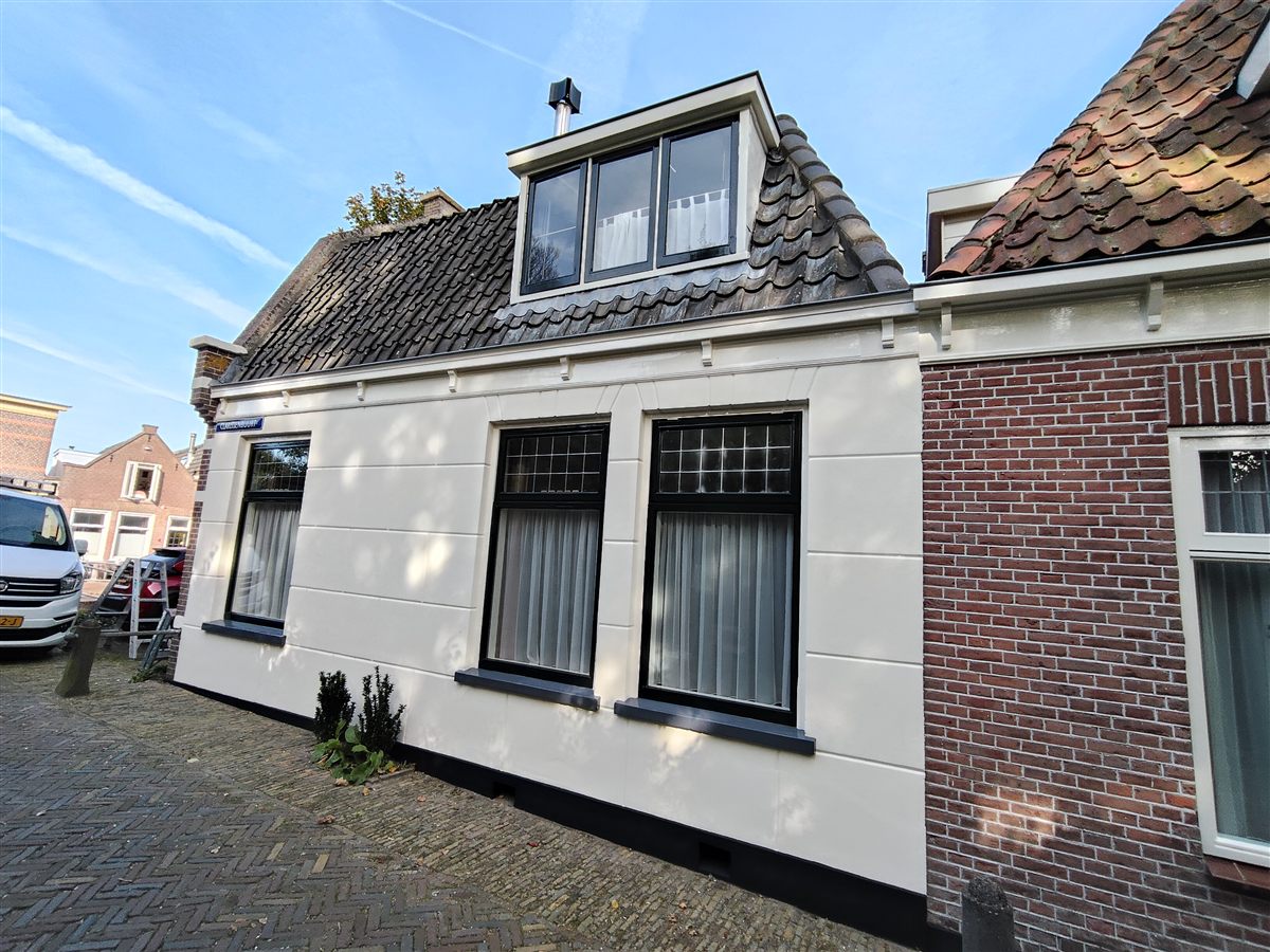 Wit geschilderde hoekwoning met zwarte kozijnen