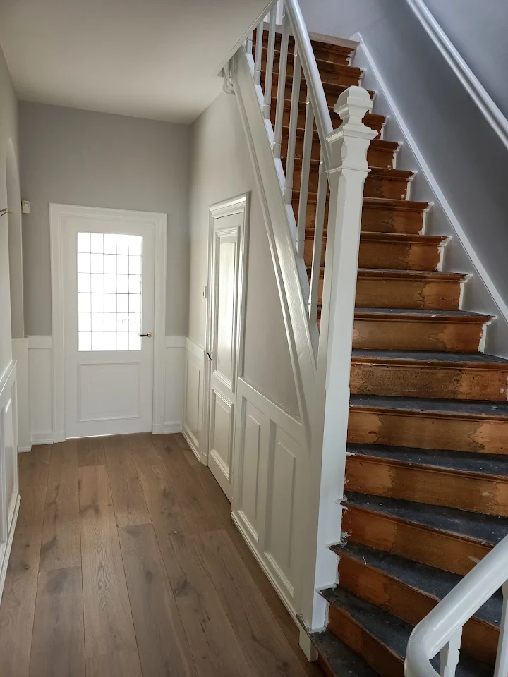 Gang met grijze muren en witte trap