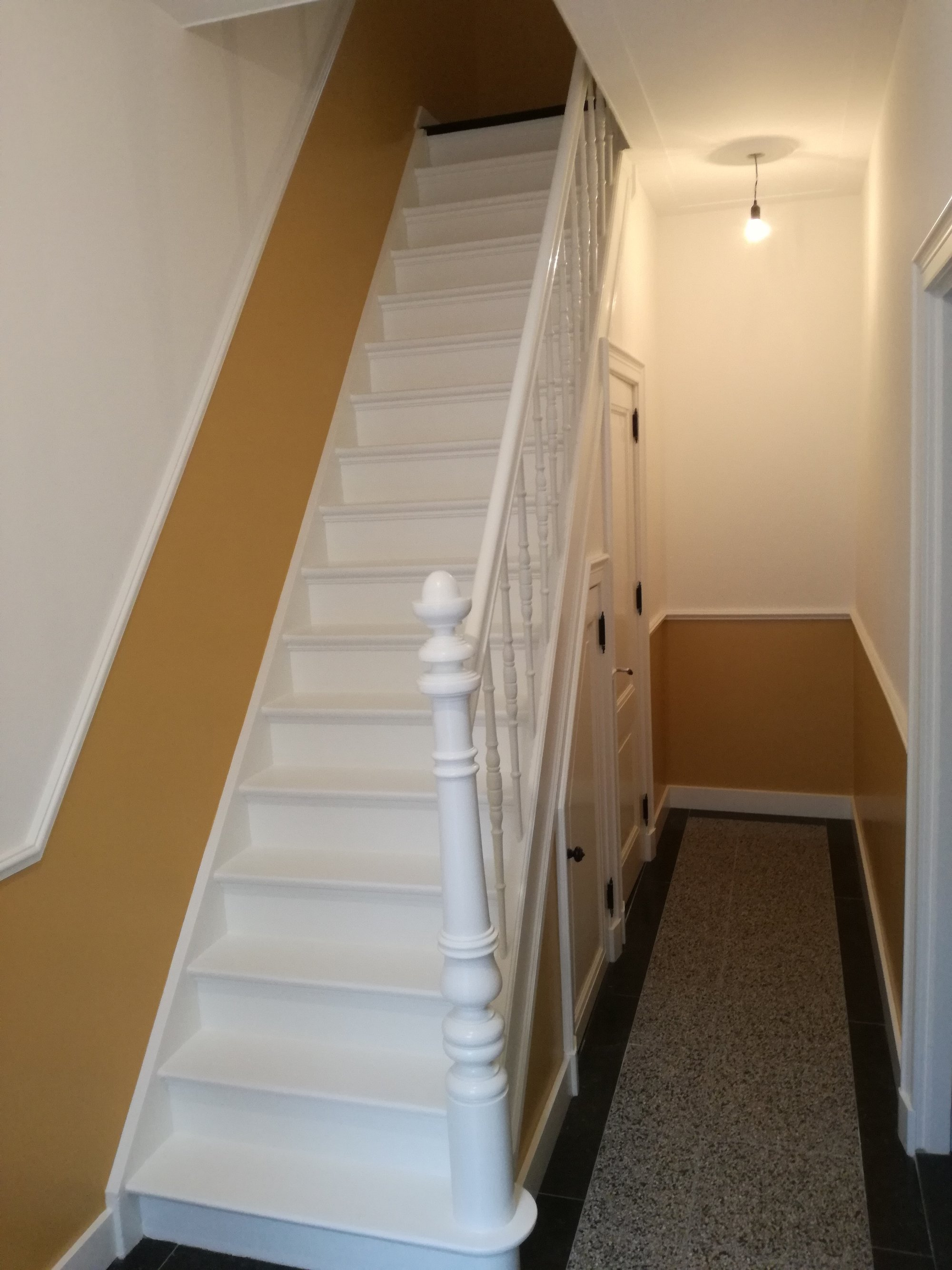 Witte trap met gele lambrisering in hal